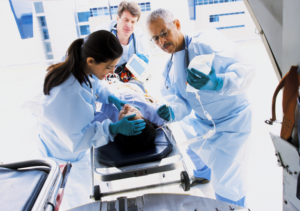 Imagen de un paciente en camilla entrando a urgencias rodeado por tres personas del personal sanitario