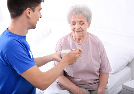 Imagen de un personal sanitario ayudando a comer a una paciente anciana